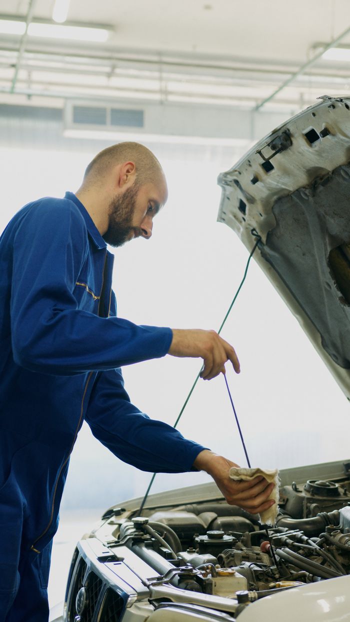 The Art of Drawing Readers In: Your attractive post title goes here Mechanic inspecting car engine oil with dipstick in an automotive repair shop.